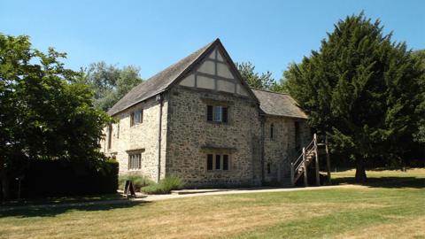side_view_of_old_house_and_garden_in_sunshine.