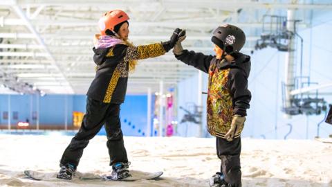 two_young_snowboarders_high_fiving.