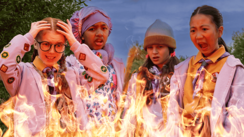 Four girls looking shocked in front of a fire