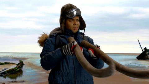 a man stands in a deserted seabed holding two mammoth tusks