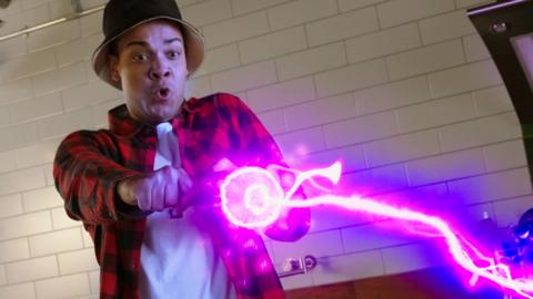 a man in a red and black plaid shirt is firing a lightning purple shrink ray