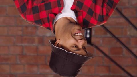 A man wearing a red and black plaid shirt is upside-down