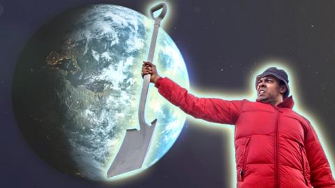 A young man in a bucket hat and a bright red coat is holding a shovel in the air triumphantly. Behind him is a large picture of the Earth in space.