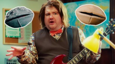 Image of a man dressed as an eccentric teacher holding a guitar with animated rocks either side.