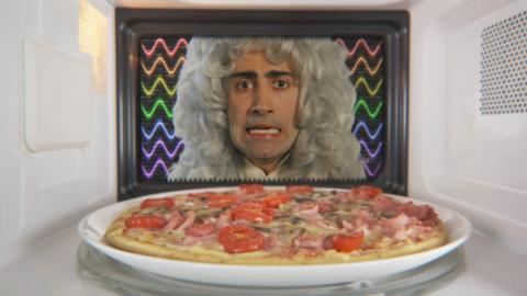 An old scientist in a wig is looking at a pizza in a microwave