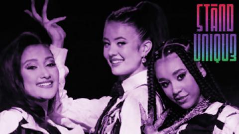 The "Stand Unique" band logo next to three young girls wearing black and white costumes