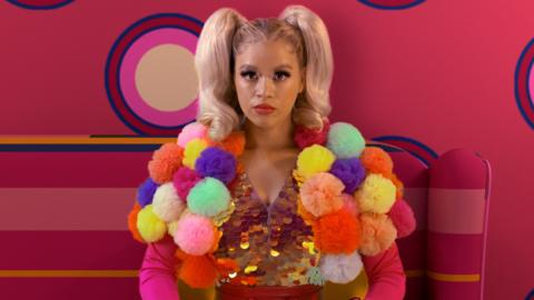 Nova Jones wearing a pom-pom costume looking neutral into camera.