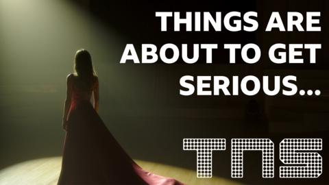 "Things are about to get serious...". A dark picture of a women in a long dress under a spotlight on stage