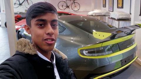 A boy in front of a supercar.