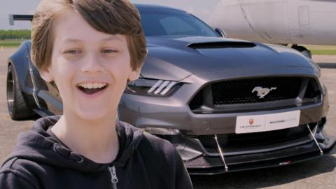 An American muscle car and a boy looking surprised.