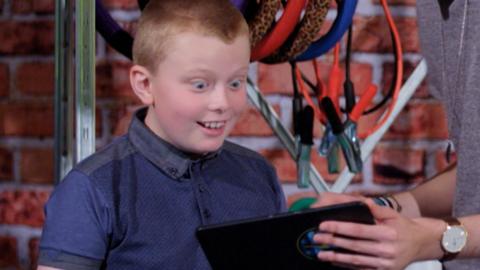 A boy looking shocked at a tablet.