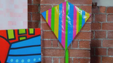 Picture of colourful handmade kite on a wall.