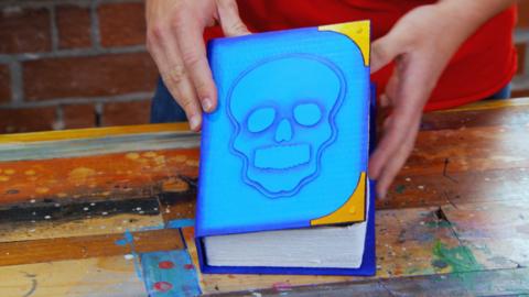 Hands holding a handmade blue box with a skull on the front.