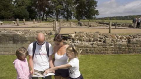 Family looking at a map , the ruins of the roman fort in the background