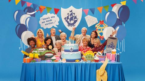 Blue Peter presenters partying around a table.