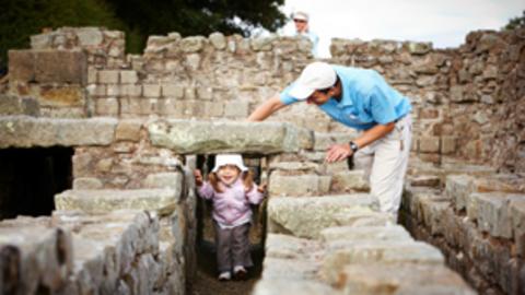 A father watching his daughter play in the ruins of the roman town