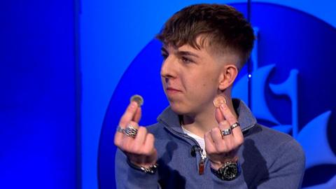 Dan Rhodes holding up two coins