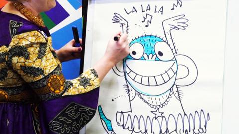 Philip Reeve and Sarah McIntyre drawing on flipcharts. Sarah is drawing a monkey doing ballet in a tutu.