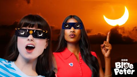 Abby and Shini wearing solar eclipse glasses whilst a partial solar eclipse happens behind them.