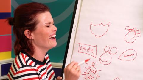 Lindsey drawing on a flip chart and laughing.