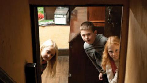 Three children peering up a staircase