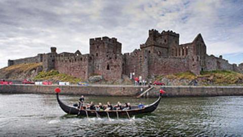A longboat race taking place in front of Peel Castle.