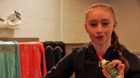 A girl smiling and holding up glue.