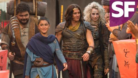 A group of warriors leaving a village while a crowd applauds them.