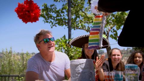 A man and a woman looks impressed as they stare at a brightly coloured rainbow layer cake.