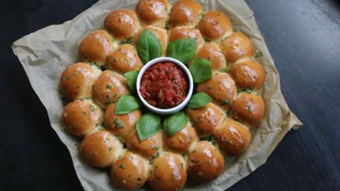A plate of dough balls with a tomato dip.