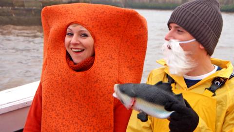 Naomi dressed as a fish finger and Ed dressed as a fisherman holding a fake fish.