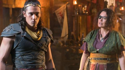 An armoured man in a golden crown looks worried while a woman in an eyepatch looks on.