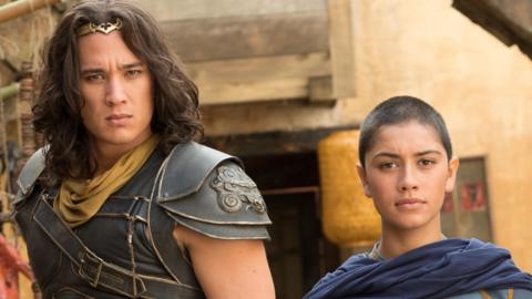 A tall man in armour and a golden crown stands next to a warrior monk in blue robes.