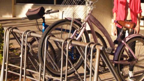 A bike locked to a rail by it's wheel.