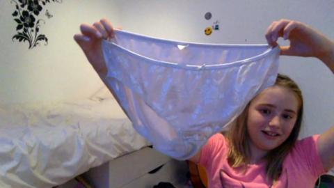 A girl holding up a pair of knickers.