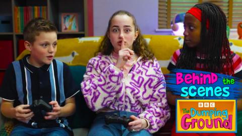 Maisie and Izzy from The Dumping Ground go behind the scenes, they are sat on a sofa playing video games.