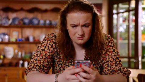 Floss from The Dumping Ground, looking confused as she looks at her phone