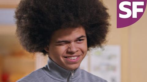 A teen boy with afro textured hair is winking cheekily, Jay from The Dumping Ground.