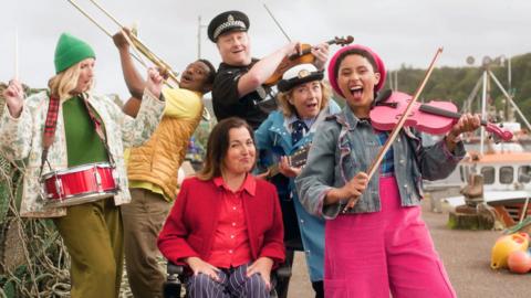 The residents of Balamory playing instruments and having a party by the harbour.
