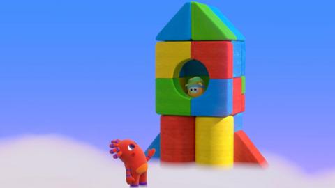 MeMo, standing looking up at a rocket made from colourful blocks, trying to coax BaBa down.