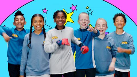 A group of young kids in football kits are cheering, singing and marching on the spot.