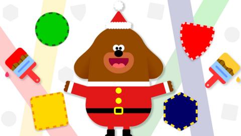 Duggee is wearing a santa suit holding paintbrushes with shapes around him.