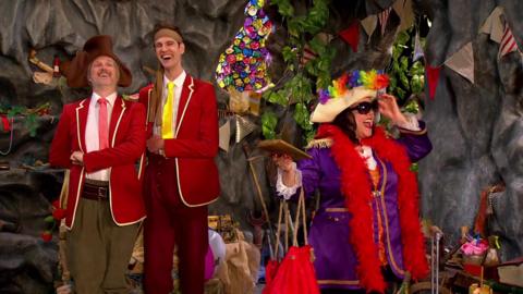 Sandy and Seaweed are smiling to themselves whilst wearing red blazers. Captain Captain is wearing sunglasses and a holiday hat.