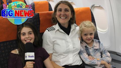 Lilian and Helena from this show are sat in seats inside an aircraft with their mum Marine, who is wearing a pilot uniform.