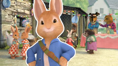 Peter Rabbit standing with his hands on his hips, in front of a spring time party scene.