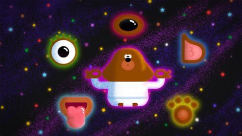 Duggee floating in space surrounded by images of a tongue, an ear, an ear, a nose and a paw print. This is representing the five different senses of taste, hear, see, smell and touch.
