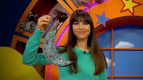 Rebecca holding a Moon mobile she has made with paper plates.