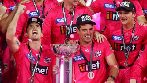 Sydney Sixers captain Moises Henriques (centre) smiles as he poses with the Big Bash trophy surrounded by team-mates