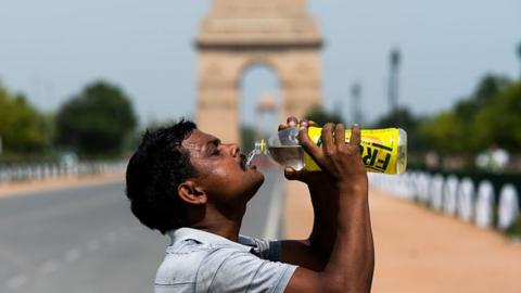 A worker taking a break from cleaning weeds near India Gate in Delhi