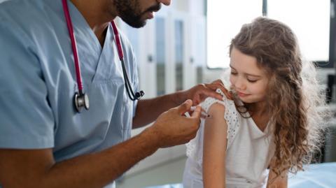 A doctor vaccinating a young girl.